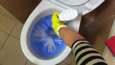 Ev kadını mavi temizleme sıvısı tuvalet kase içine yağıyor