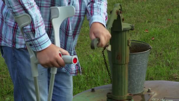 Hombre Con Muletas Bombeando Agua Cubo — Vídeo de stock