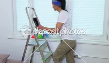 Kadın pencere panjur yakınındaki bir toz fırçası ile