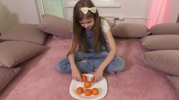 Flicka Sortering Klementiner Och Sitter Sängen — Stockvideo