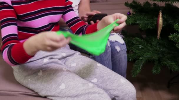 小女孩与粘液和母亲背后使用智能手机 — 图库视频影像