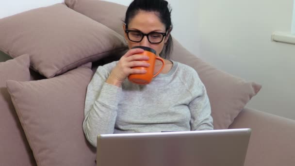 Kvinna Dricker Kaffe Och Skrattar Nära Laptop Soffan — Stockvideo