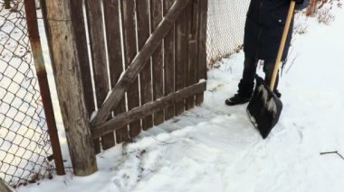 Kadın Bahçe kapıları etrafında kar kazmak