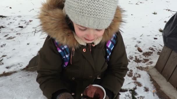 Κοριτσάκι Τρώει Πουτίγκα Σοκολάτας Στο Παγκάκι Στο Πάρκο — Αρχείο Βίντεο