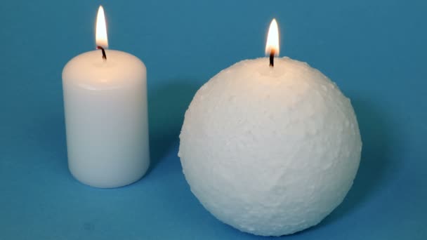 Zwei Weiße Brennende Kerzen Auf Blau — Stockvideo