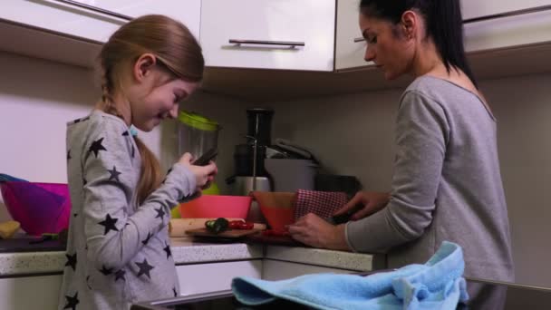 Hija Usando Smartphone Cerca Madre Cocina — Vídeos de Stock