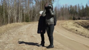 Ormanda yolda sırt çantası ve dürbün ile anne ve kızı