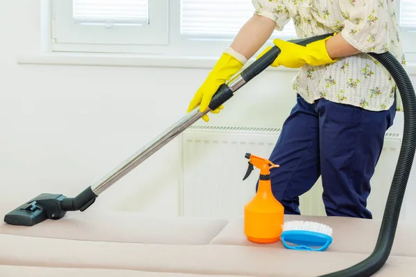 Woman cleaning a couch with a vacuum cleaner