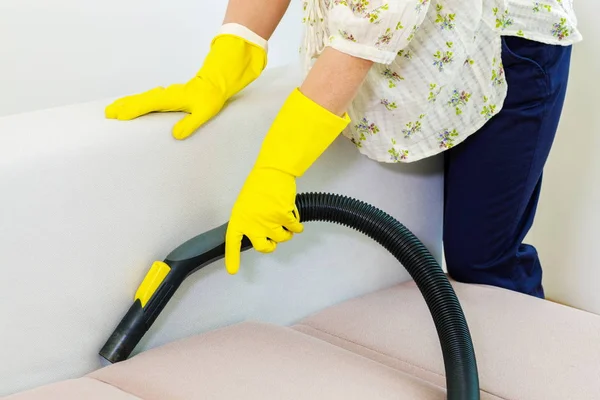 Woman cleaning couch at home