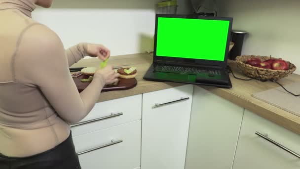 Frau Schaut Laptop Mit Grünem Bildschirm Küche Und Macht Burger — Stockvideo