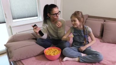 Kızı ve anne konuşma ve Tv yakınında cips yeme