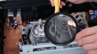 VCR oynatıcının yanında büyüteç kullanan kadın