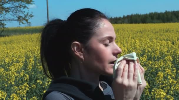 菜の花畑での女性のくしゃみ 花粉アレルギーの概念 — ストック動画