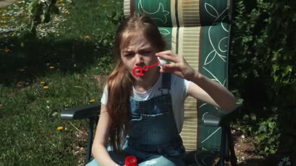 Menina Bonito Sentado Cadeira Jardim Soprando Bolhas Sabão — Vídeo de Stock