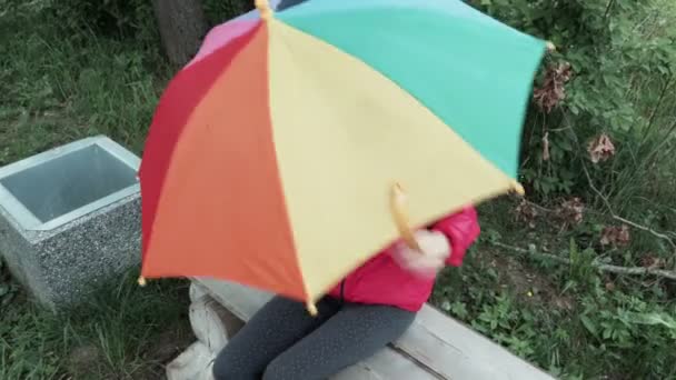 Nettes Kleines Mädchen Spielt Mit Regenschirm Und Singt Auf Bank — Stockvideo