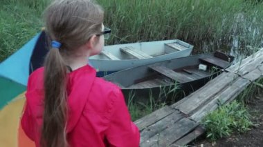 Yağmurlu bir günde göl yakınında şemsiyeli küçük kız