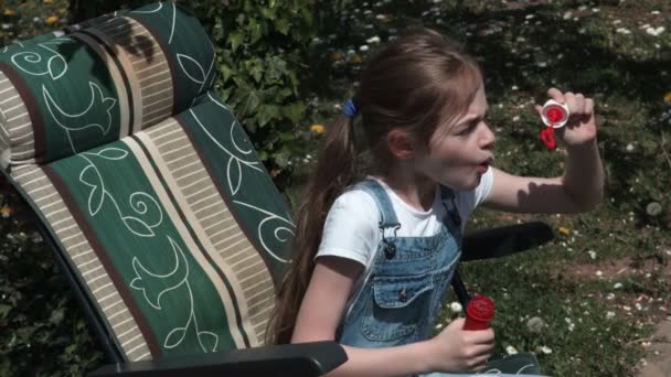 可爱的年轻女孩在花园里吹肥皂泡 — 图库视频影像
