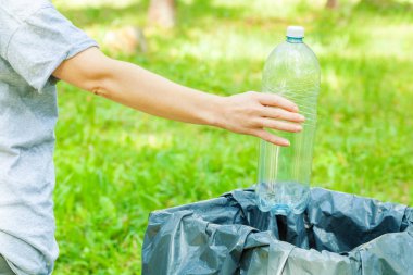 Parkta çöp kutusuna boş plastik su şişesi atan kadın