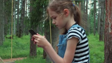 Parkta akıllı telefon kullanan küçük kız yakın çekim