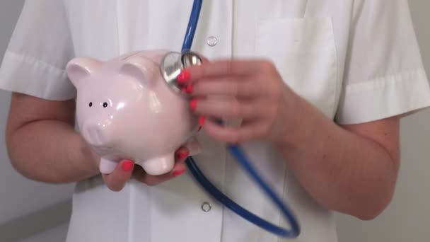 女性医師とともに聴診器と貯金箱 — ストック動画
