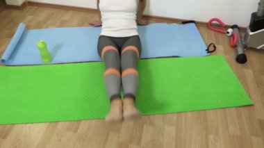 Karın kasları için egzersiz yapan ve spor minderinde su içen kadın.