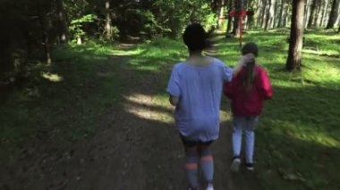  Kızı ve annesi birlikte parkta koşuyorlar, yazın güneşli zamanlarda spor yapıyorlar. Kadın ve kız açık havada