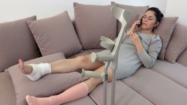 Woman Crutches Lying Couch Using Smartphone — ストック動画