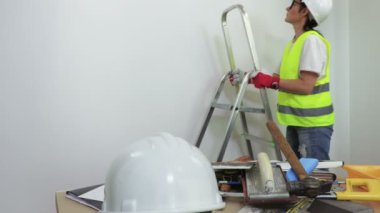 Duvarın yanındaki merdivenlerde çalışan kadın inşaat işçisi.