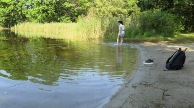  Kadın yürüyüşçü yazın yürüdükten sonra gölde dinleniyor.