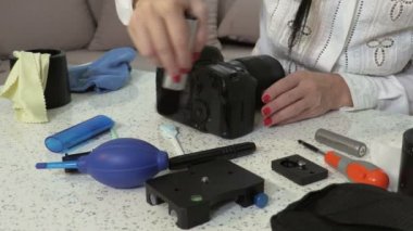 Kameranın gövdesini temizlemek için hava üfleyici ve fırça kullanan kadın