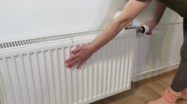 Isıtma radyatörünün ısınmasını denetleyen kadın. Enerji tasarrufu kavramı.