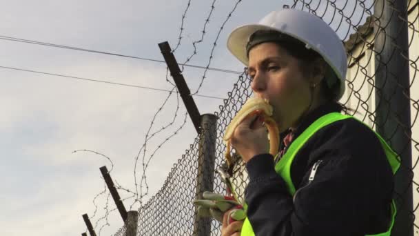 Γυναίκα Μηχανικός Τρώει Στο Διάλειμμα Κοντά Φράχτη — Αρχείο Βίντεο