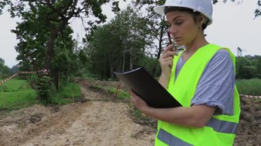 Kadın inşaat mühendisi düşünüyor ve yazıyor.