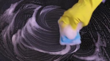 Kadın mutfakta ocağı temizliyor.