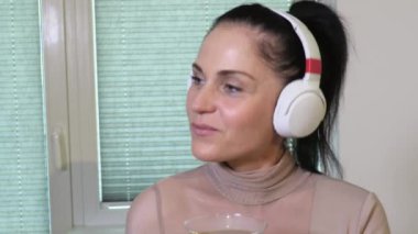 Kulaklık takan ve kokteyl içen kadın.