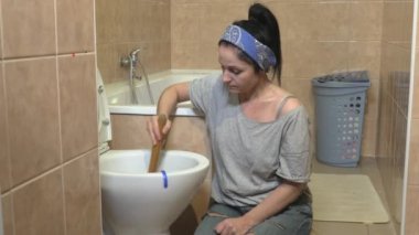 Tuvalet kapağını açmak için pompa kullanan kadın.