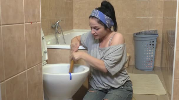 女人在臭气熏天的厕所里用柱塞 — 图库视频影像
