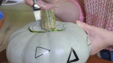 Bıçaklı kadın, tahta mutfak tahtasının üzerinde balkabağı hazırlıyor.