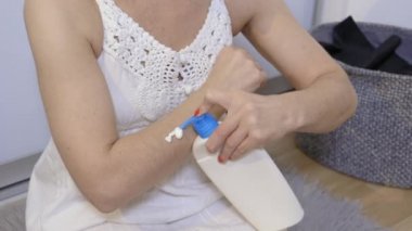 Kadın kollarında vücut losyonu kullanıyor.