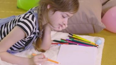 Renkli kalemlerle çizen küçük kız.