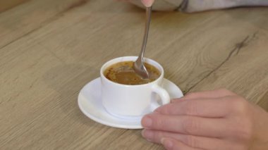 Beyaz fincanda kahve karıştıran kadın.