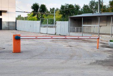 Otomatik iner kalkar parmaklığı, topraklarına giriş yolu, turuncu kırmızı bariyer, engelleme metal çit, binalar, asfalt