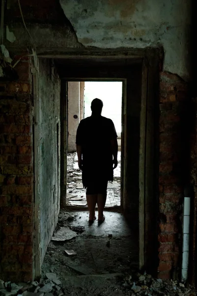 Terk edilmiş bina, karanlık koridor, karanlık siluet, kapı aralığı aydınlık, harabeler, kırık pencereler, pas, bitmemiş bir adam.