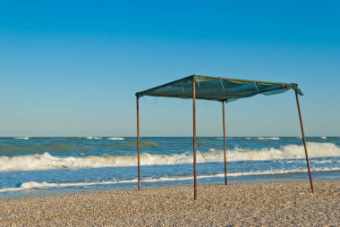 Yaz parlak güneşin hafta sonu tatil dalga köpüğü açık bir günde kumaş ve metal, deniz ve gökyüzü, bulutlar karaya çerçevede tente çardak gölgelik yapılmış