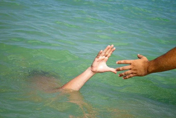 A man's hand drowns in water calling for help, man helps rescue, against the background of the sea and sky clouds summer, sun, weekend, can not swim, rescue, vacation wave foam