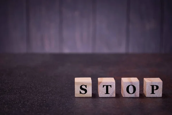 The word stop on wooden cubes, on a dark background, light wooden cubes signs, symbols signs, business office, site content