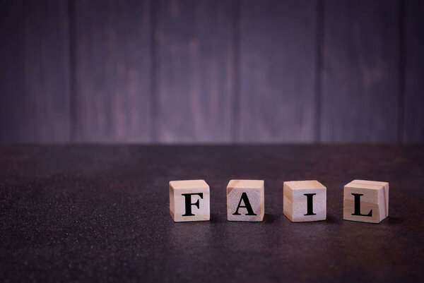 The word fail on wooden cubes, on a dark background, light wooden cubes signs, symbols signs, business office, site content