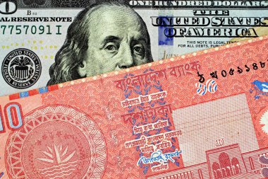 Bir Amerikan yüz dolarlık banknot kırmızı Bangladeşli on taka notla bir makro görüntüsünü kapat