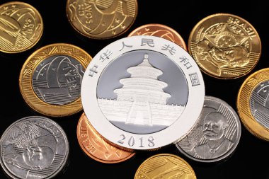 Bir ons gümüş Çin panda yazı tura yansıtıcı siyah bir arka plan ile çeşitli Brezilyalı sikkelerin bir görüntüyü kapat 