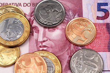 A close up image of a purple, five Brazilian reias bank note with assorted Brazilian coins in macro clipart